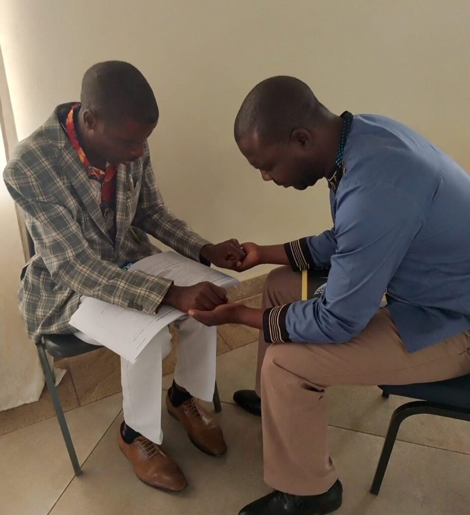 2 men sitting and praying together.