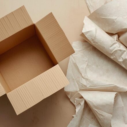An empty box that has been opened with discarded paper around it